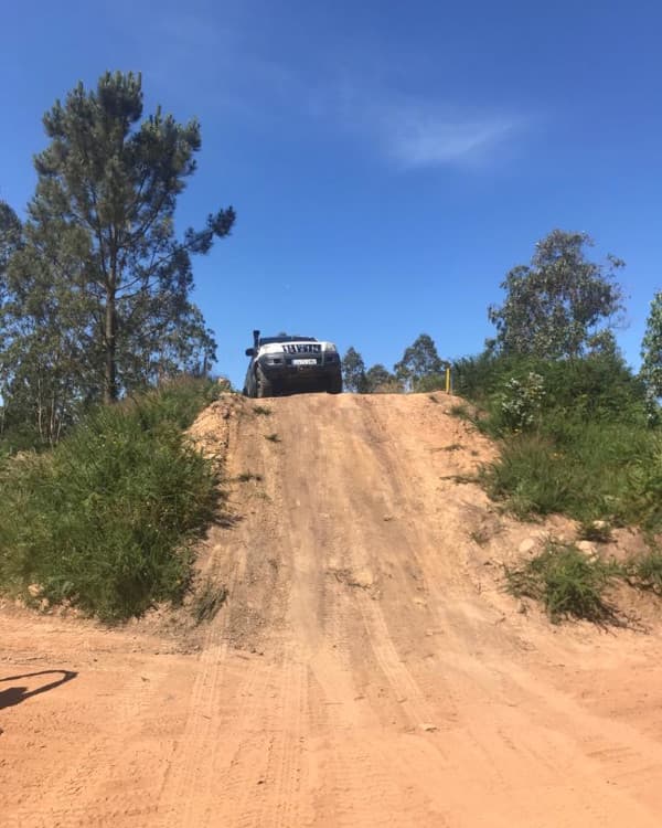 Dos todoterrenos en lo alto de una rampa de tierra, recortados contra el cielo.