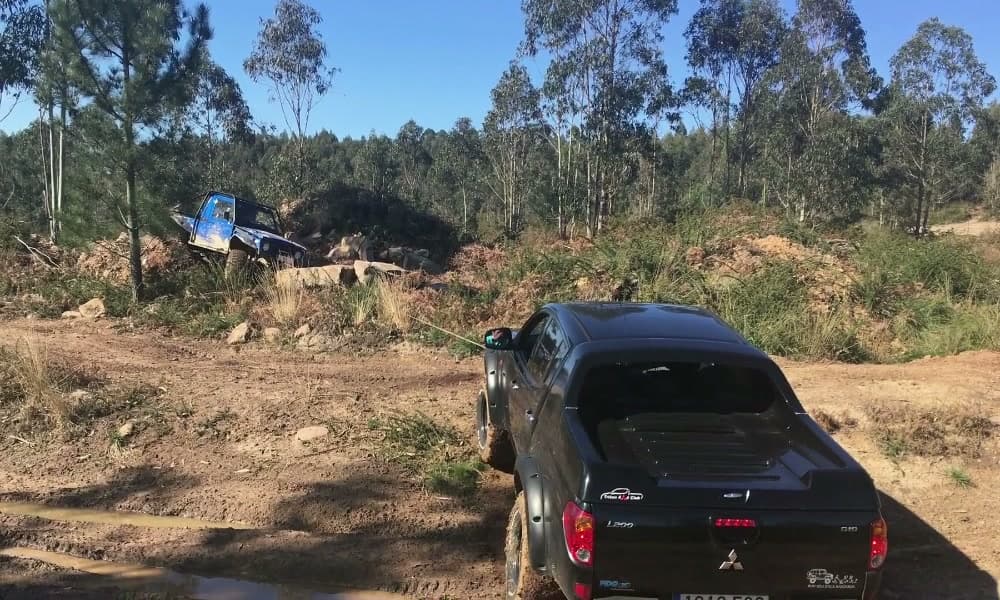 Pick-up negro junto a un charco grande en una pista de tierra del recinto.